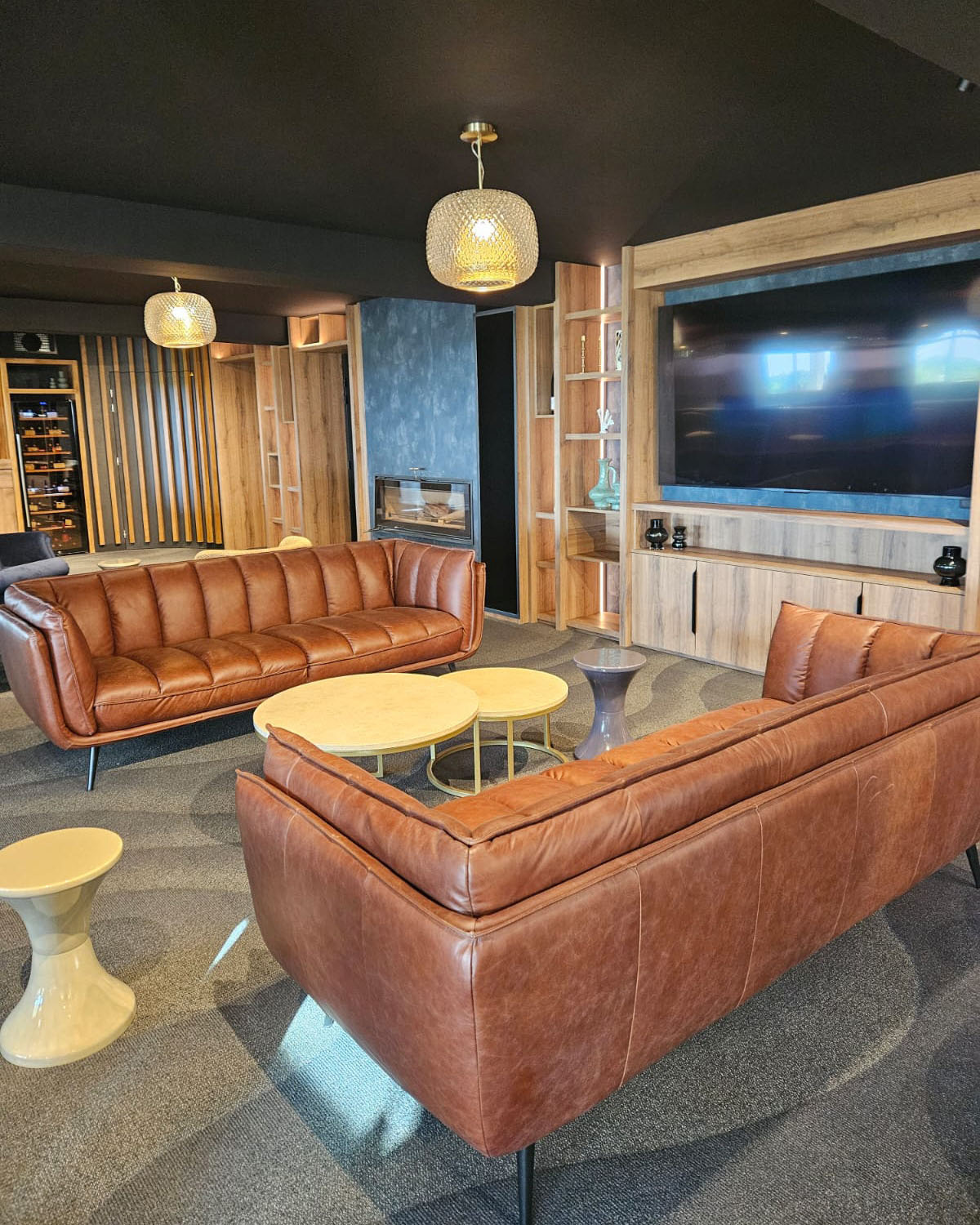 Salon avec canapé marron en cuir face à face avec une télé sur la droite.